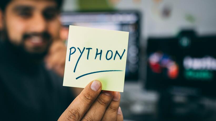 Man holding card that says Python, indicates you need Python before you can use django